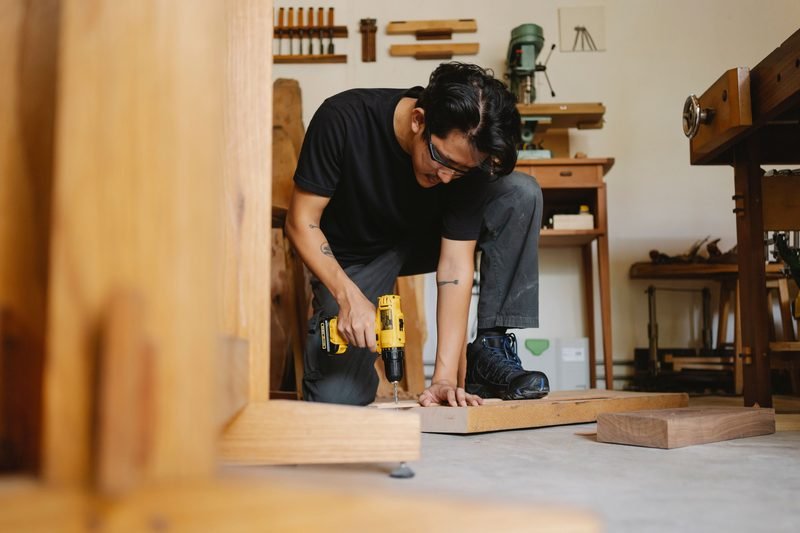Craftsman assembling wooden furniture with a power drill